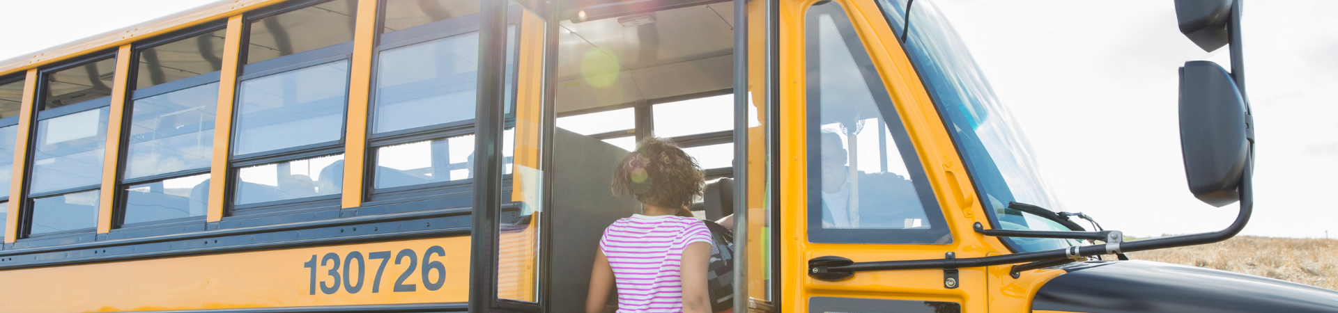 Children board a yellow school bus.