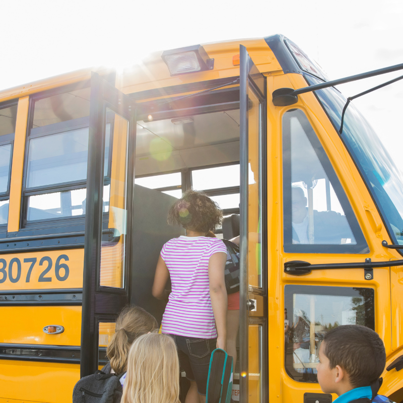 Children board a yellow school bus.