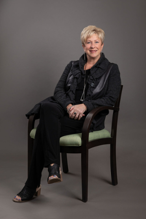 Lynn Logan seated in a green padded, wooden chair