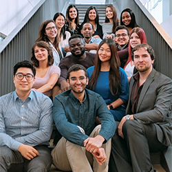 group of 2019 QES scholars sitting on a narrow staircase, 15 scholars in total with each row sitting further up the stairs