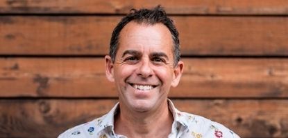 Smiling man in front of wood panels