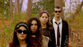 Four fashionable people stand alongside each other in a promotional photo