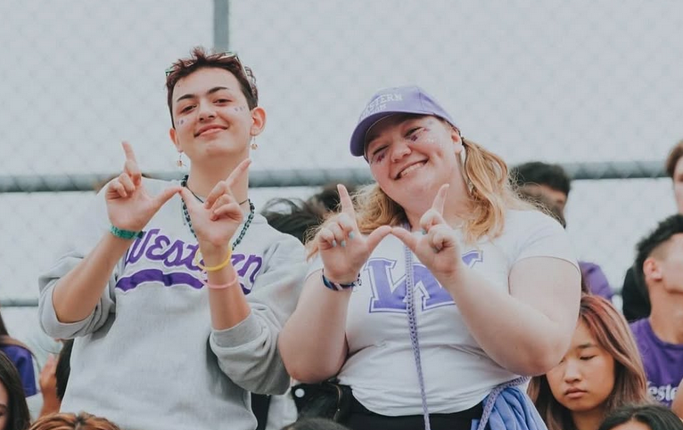 Two students flash Western W in the stands at an event