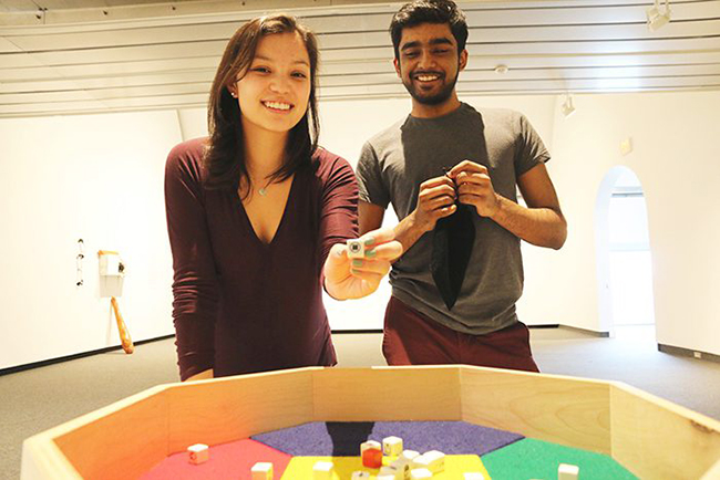 Two students stand in front of an art installation in a Museum