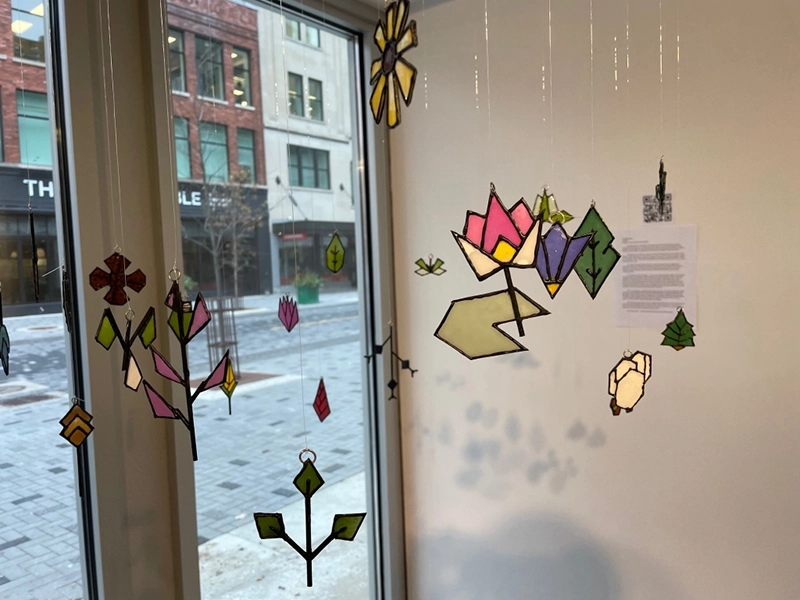 Stained glass artworks are suspended in a gallery