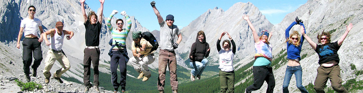 alumni from 2010 synchronized jump on the spot with Rocky Mountains in the background