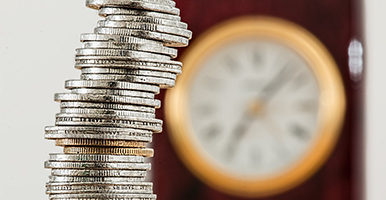 A stack of coins with a clock in the background symbolizing that the timely payment of fees is always appreciated but sometimes students do need Financial Support