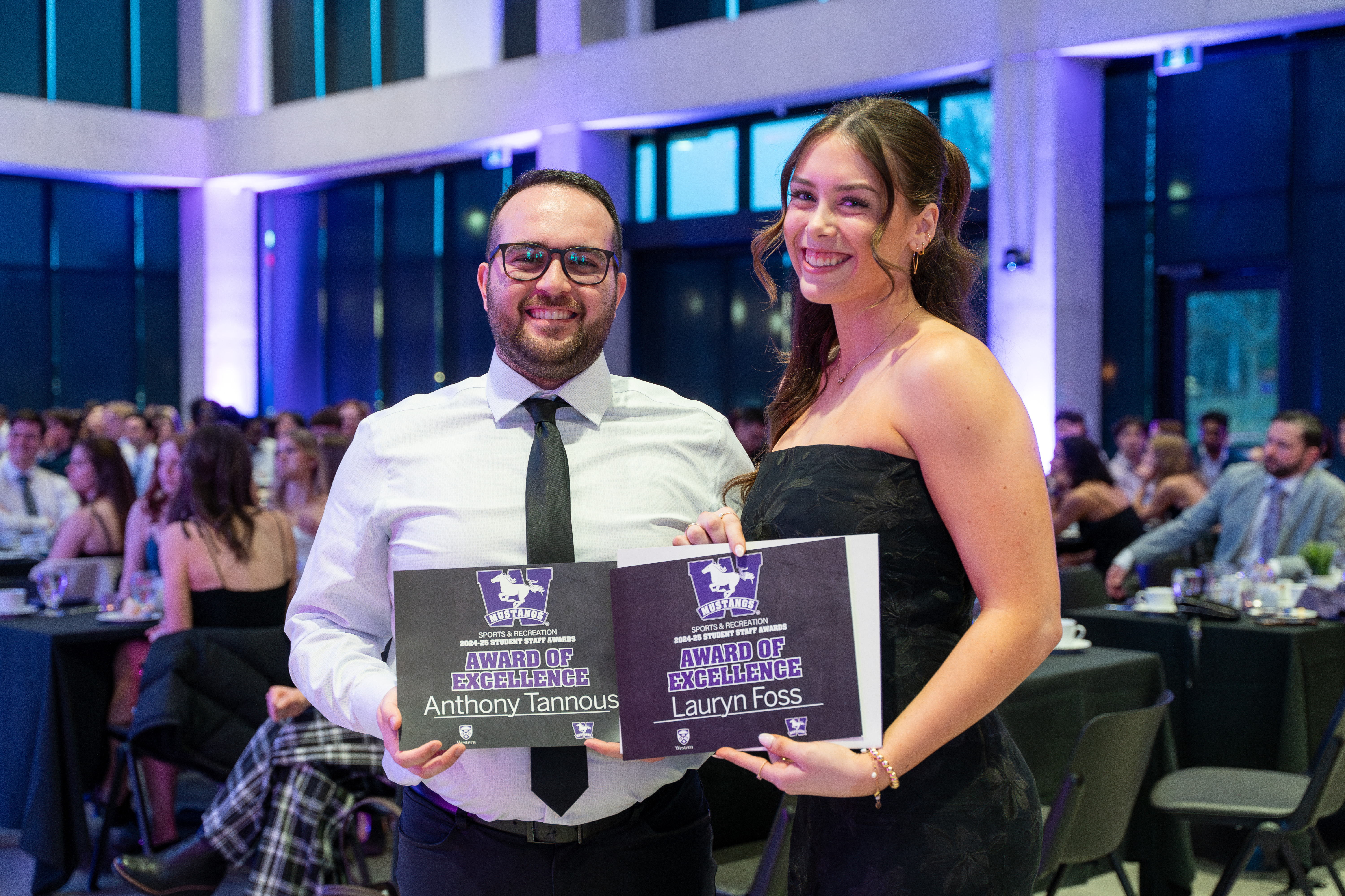 Photo of 2 people displaying award certificates, smiling