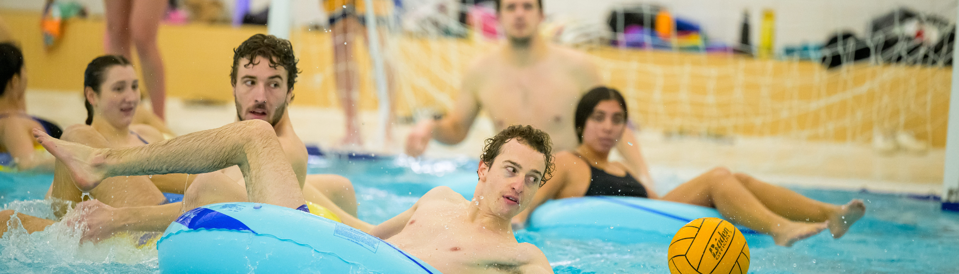 Group of people playing innertube waterpolo in a pool