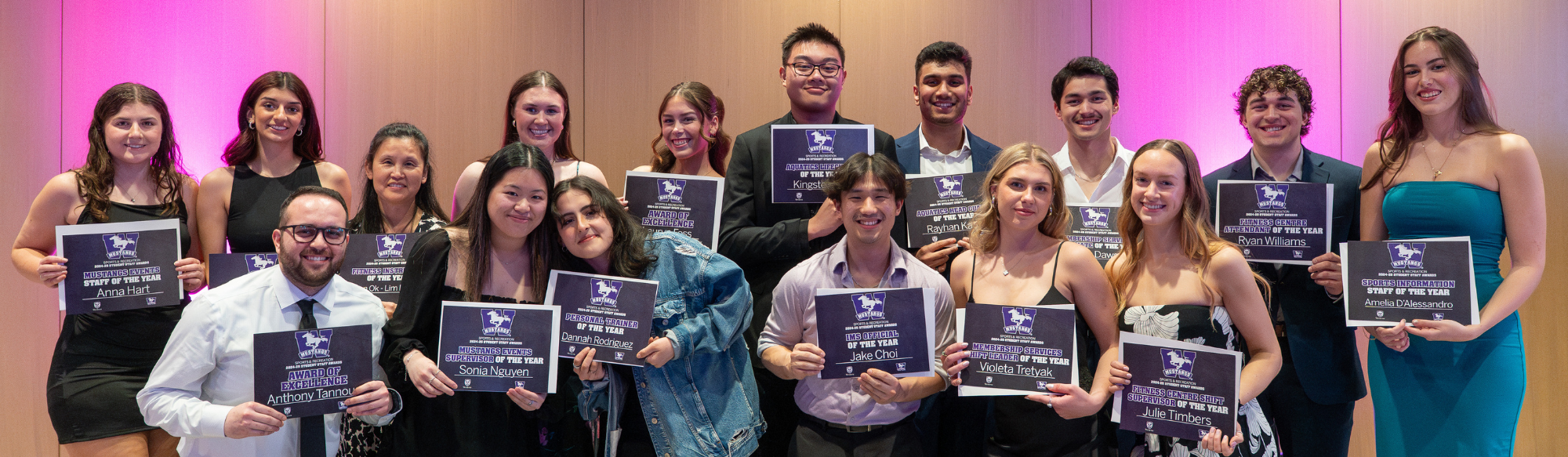 Student Staff award winners standing and seated in front of inflatable Mustangs W (purple)