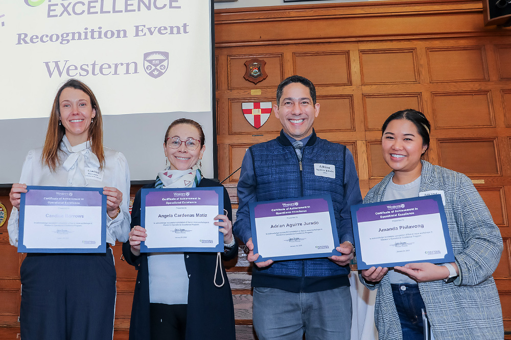 Four staff members hold their certificate of achievement.