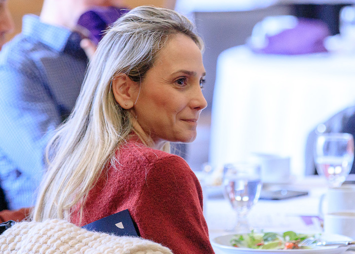 A staff participant sits at a table during an Operational Excellence recognition ceremony.