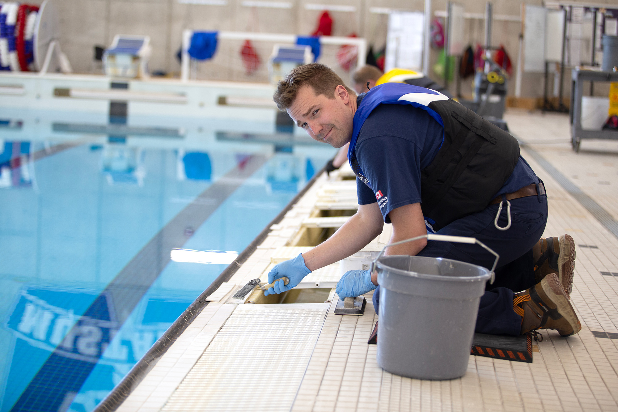 Carpenter Michael Sudds performs some tile repair work on the pool inside Campus Recreation.