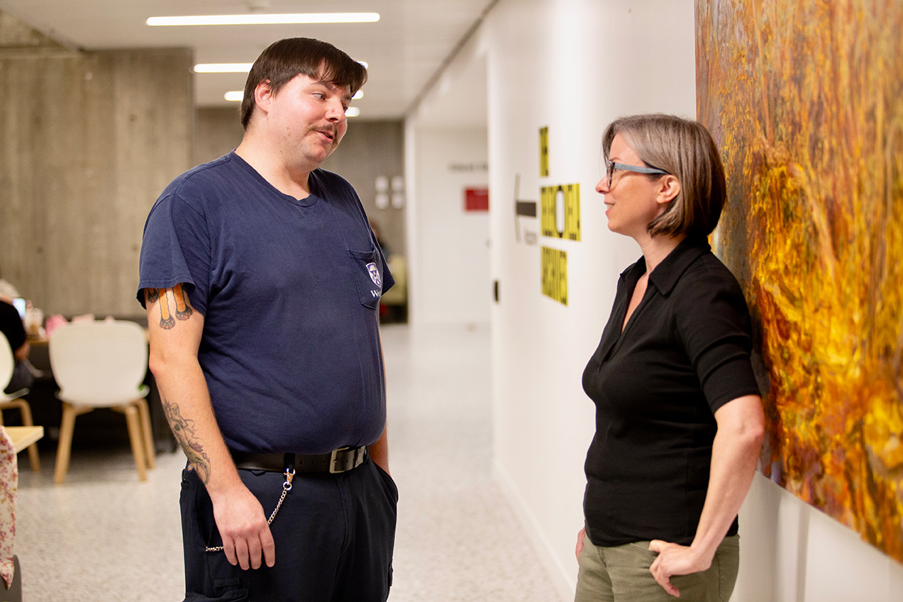 Zach Riordan and Jennifer Robinson chat in the main atrium of Weldon Library.