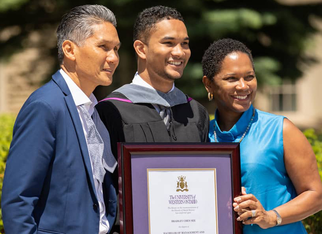 Two men jumping in the air holding their diplomas