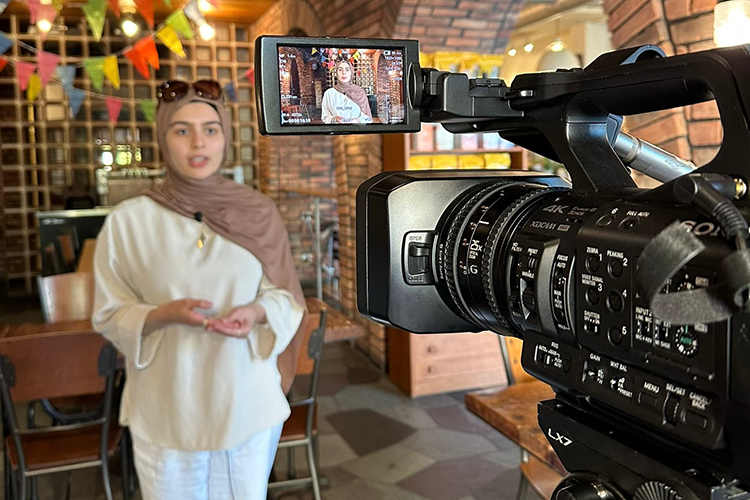 A student being recorded by a news camera in a restaurant