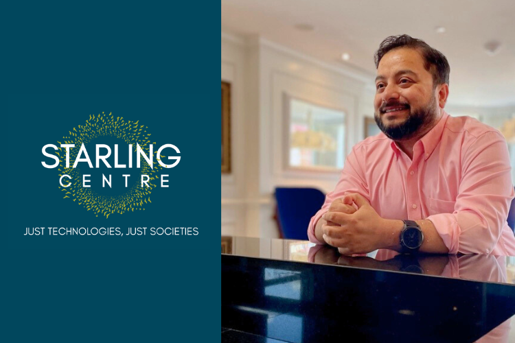 Shion Guha sits at a desk wearing a pink shirt