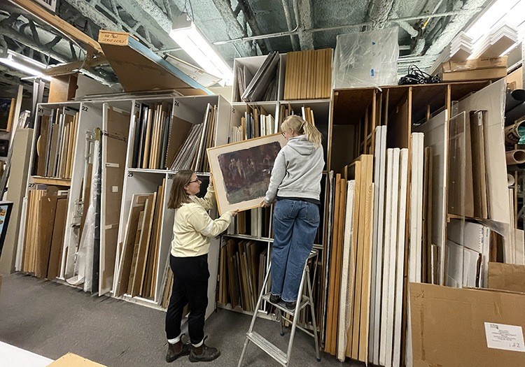 Collections Assistant Emily, and Collections Volunteer Kath handle artwork in the McIntosh Vault