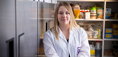 Student wearing lab coat smiling at camera