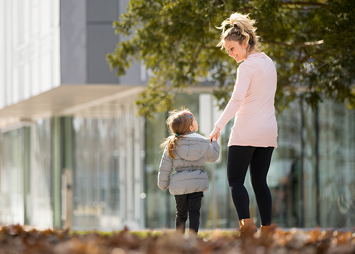 A child with a parent walking on campus.