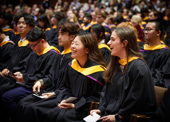 Students seated smiling and attending convocation.
