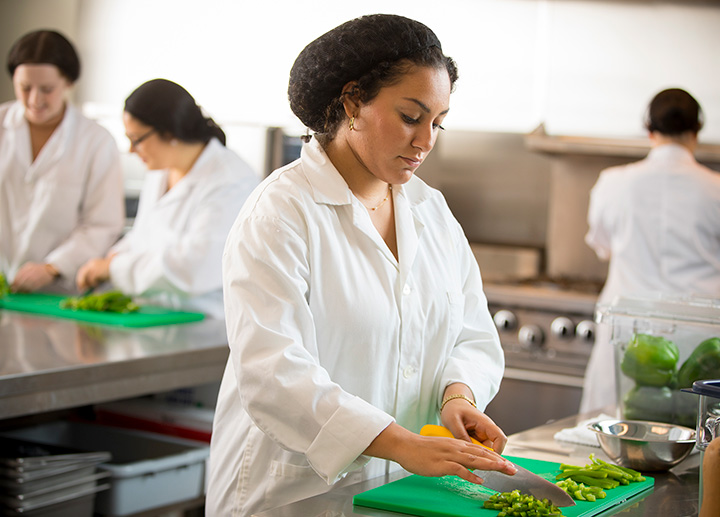 A student preparing food in the commercial kitchen.