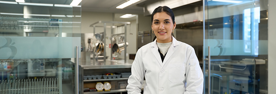 student stands in front of doors to commercial kitchen