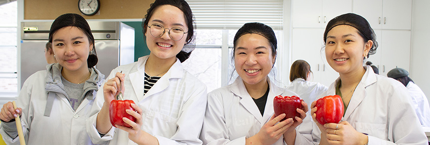Foods and Nurition students smiling and holding peppers.