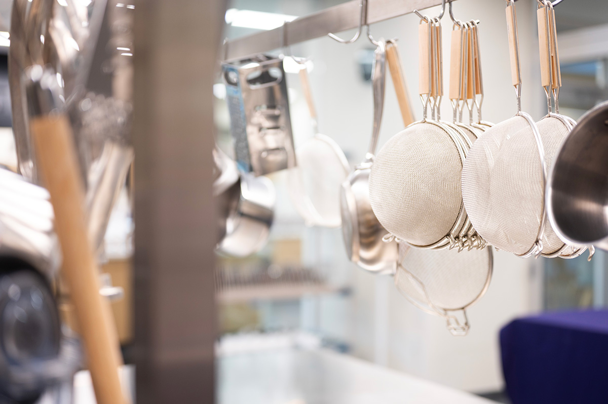 A closeup displaying strainers and other cookware in the commercial kitchen.