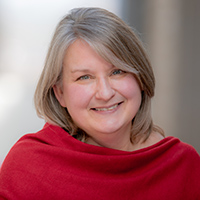 A headshot of Angela Roberts wearing a red scarf or shawl on her shoulders