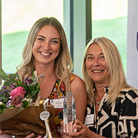 And alumni award winner with the director of the School of Nursing, holding the award and flowers
