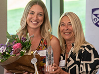 And alumni award winner with the director of the School of Nursing, holding the award and flowers