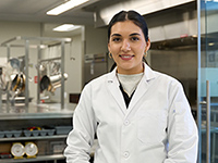 student standing at counter in a food lab wearing a lab coat