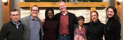 Picture of 7 people standing together in front of a large fireplace