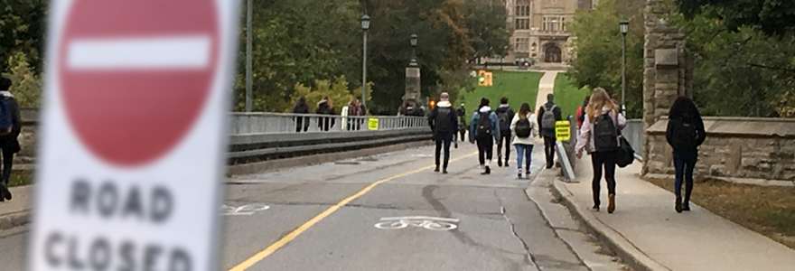 People crossing the bridge with a 'road closed' sign in the foreground