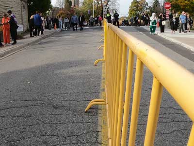Lambton Dr with a yellow fence running up the middle of the road with people in gathered in the distance.