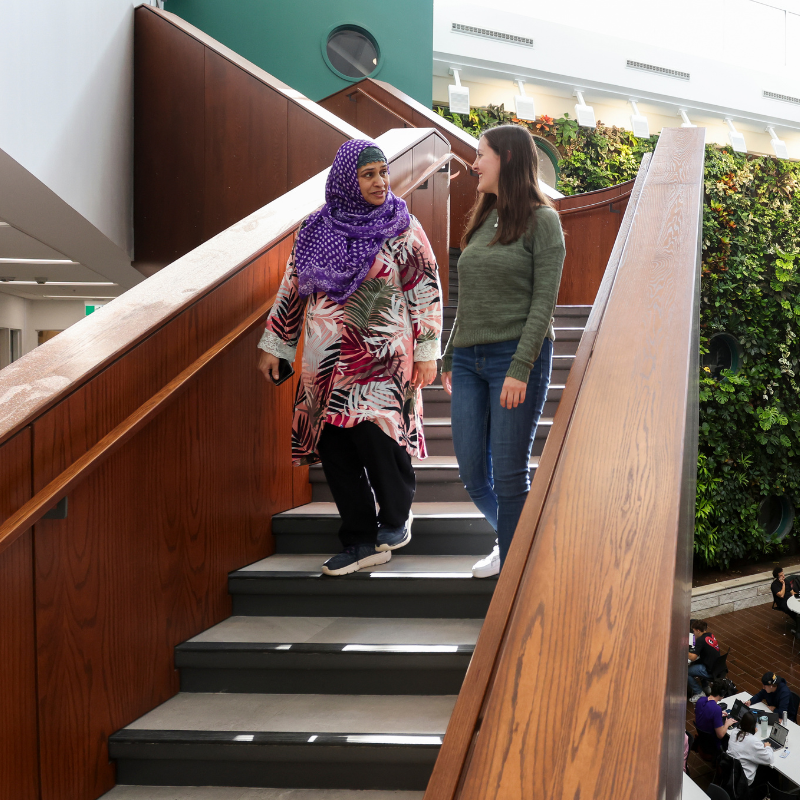 Two women descend stairs in Thames Hall.