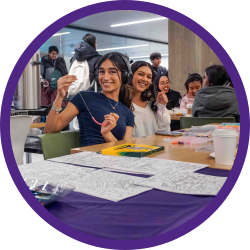 a student posing for a photo, making a friendship bracelet.
