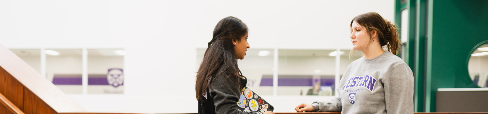 Two students speak on a staircase.