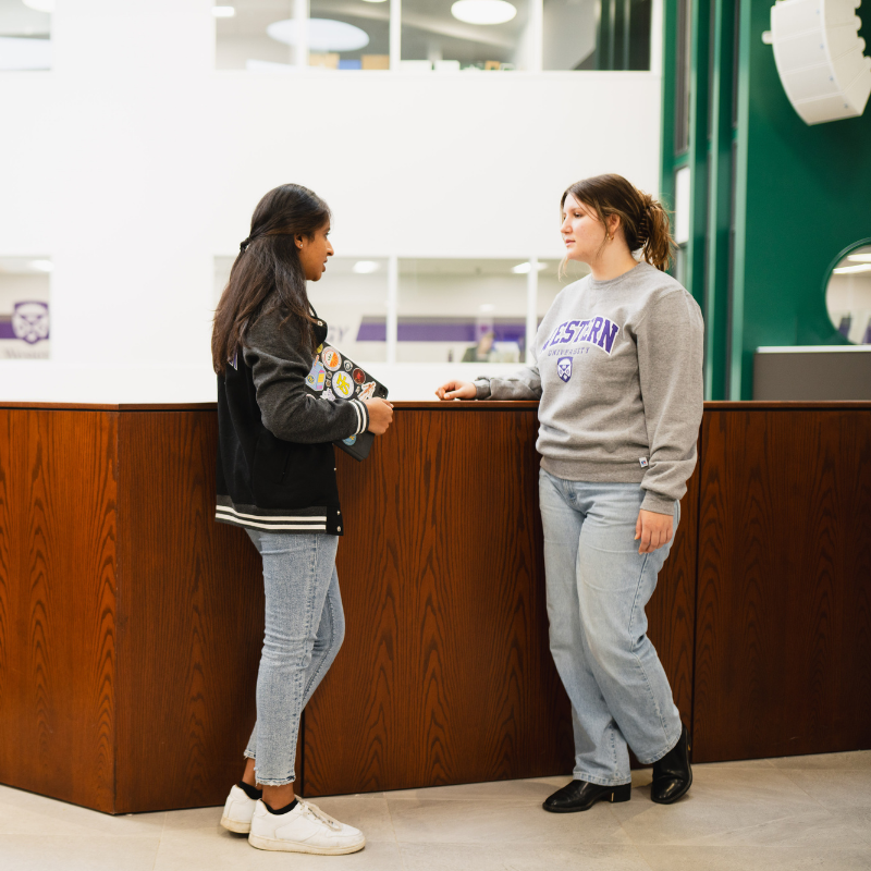 Two students speak on a staircase.