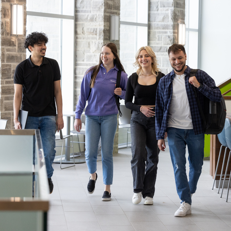 Four students walk inside the nursing building.
