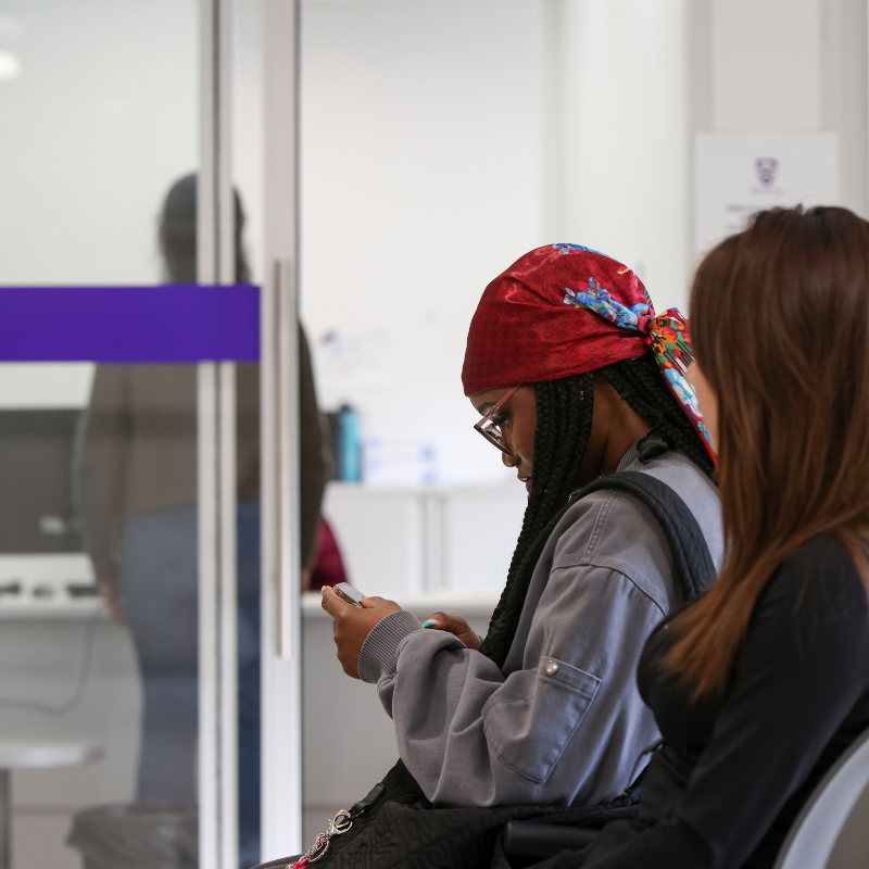 Two young women wait in a health clinic.