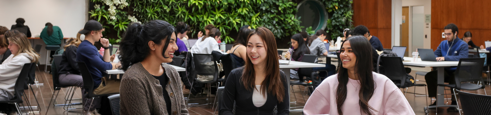Three students sit together in a busy space.
