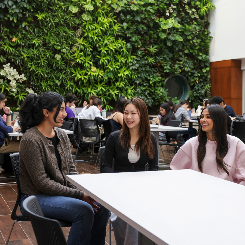 Three students sit together in a busy space.