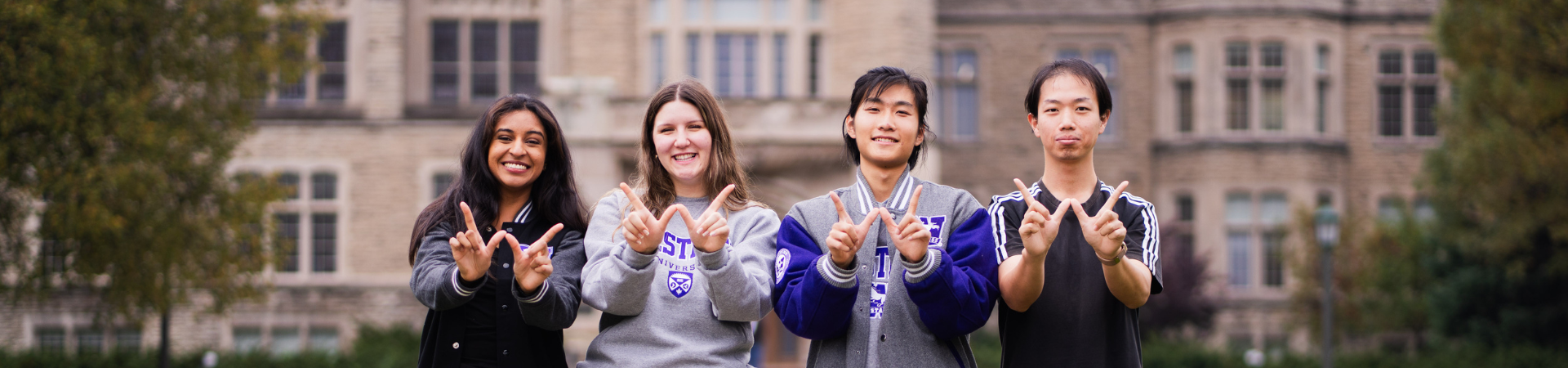 Four students holding their hands in the shape of a W for Western.