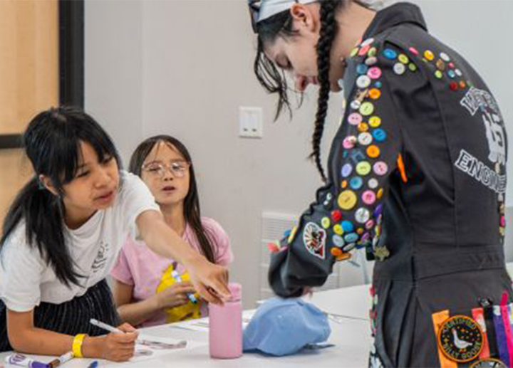 Two students working on a craft project with a camp counselor 