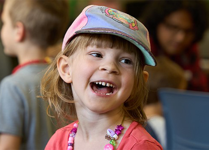 A young girl smiling with a hat on