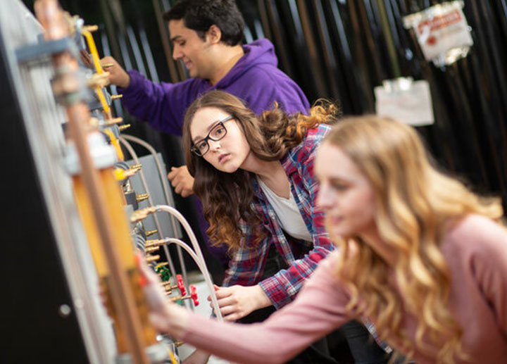 Group on young students changing wires and inspecting connections on electrical module