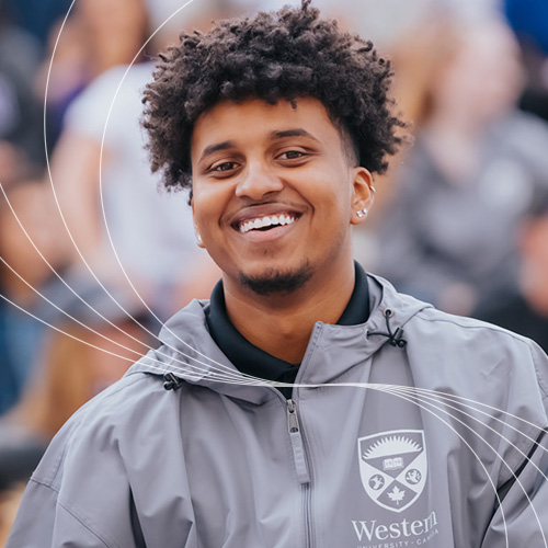Student standing in front of a blurred crowd smiling