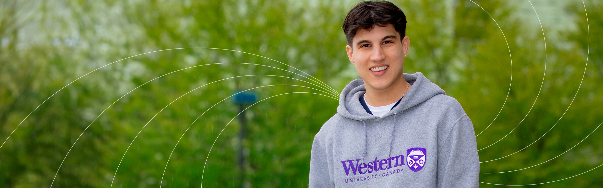 Demo Kaltabanis sitting outside in front of greenery with white Western impact lines behind.